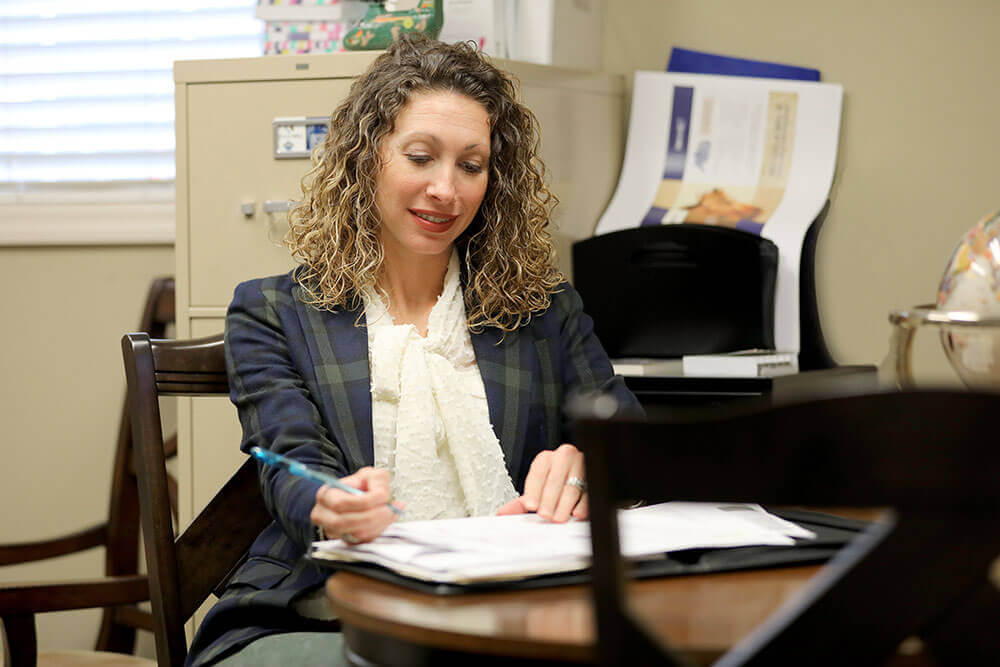 woman with curly hair writing in a notebook