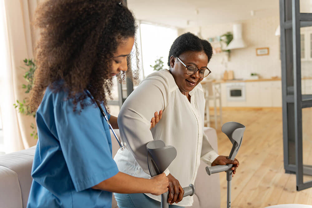 assistant helping patient into crutches