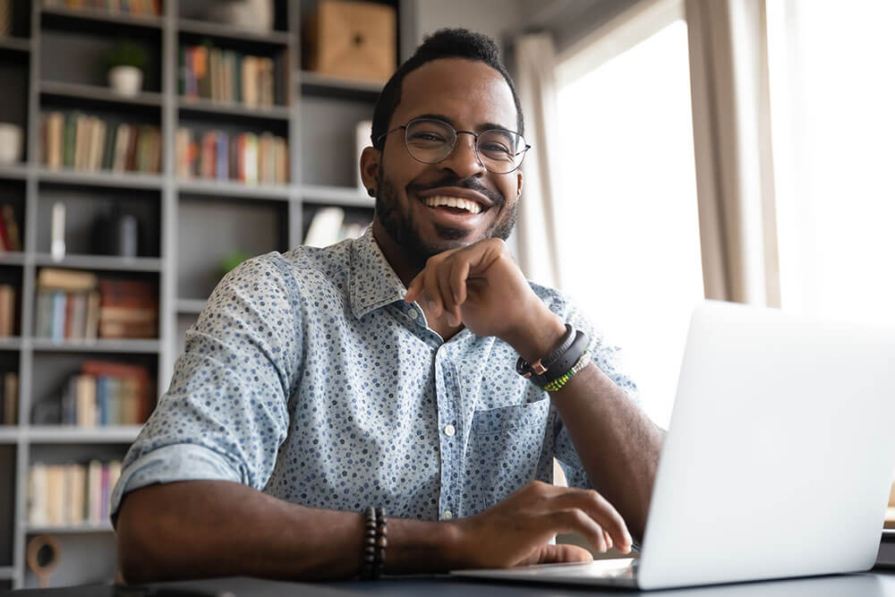 smiling man at a laptop in his living room