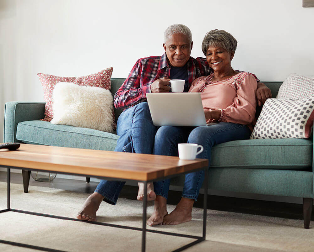 senior couple on couch looking at a laptop